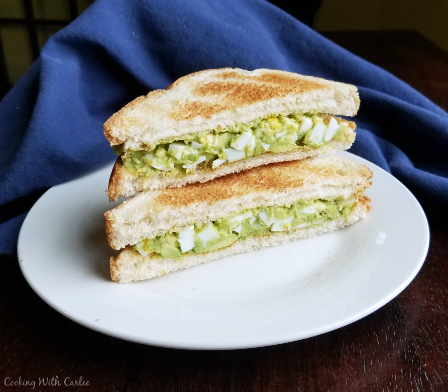 stack of 2 halves of an avocado egg salad sandwich.