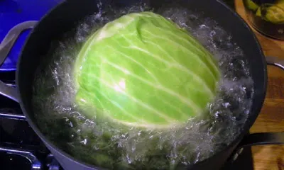 Boiling a head of cabbage for stuffed cabbage.