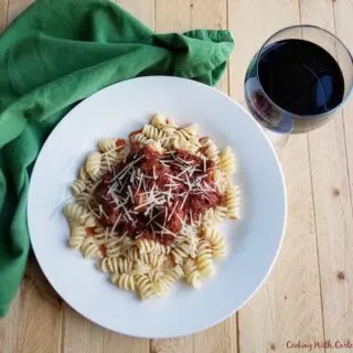 plate of pasta topped with meatballs and tomato sauce.