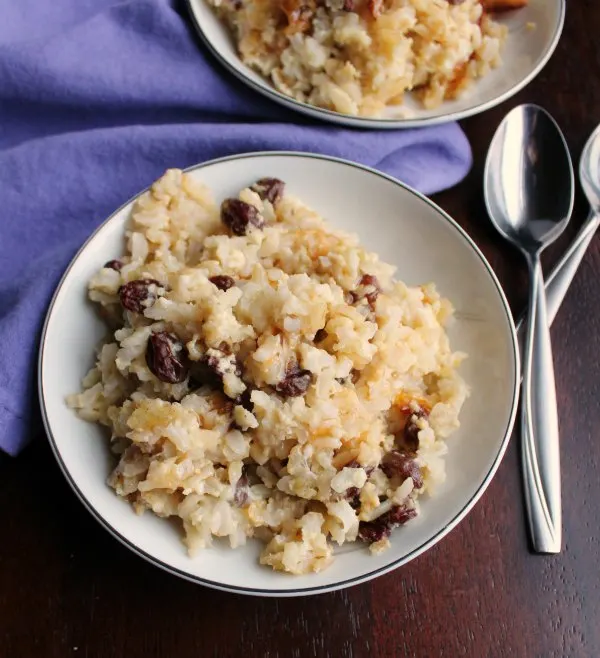 close bowl of baked rice pudding with raisins and spoons.