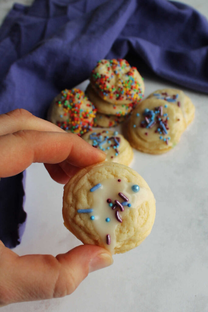 hand holding glazed sweetened condensed milk cookies with sprinkles. 