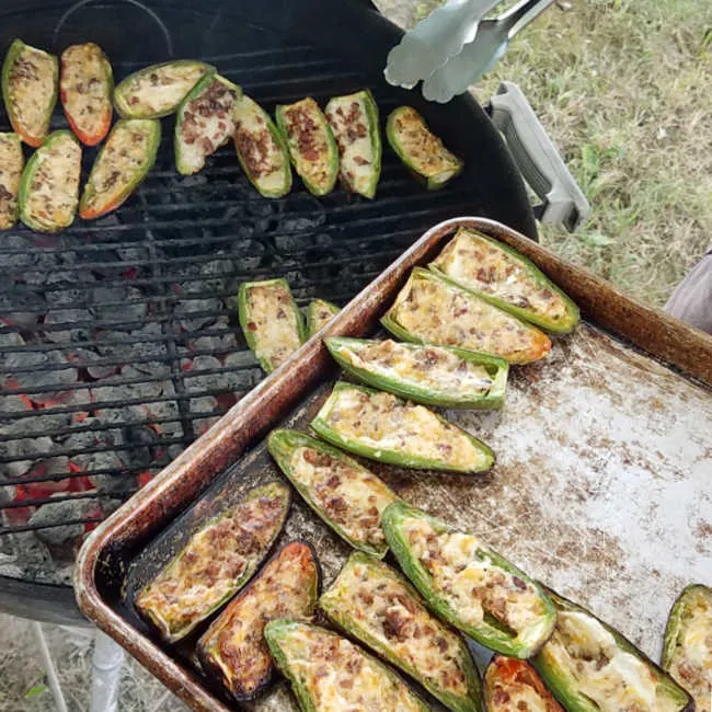 Taking jalapeno halves stuffed with cream cheese and bits of bacon off the grill.