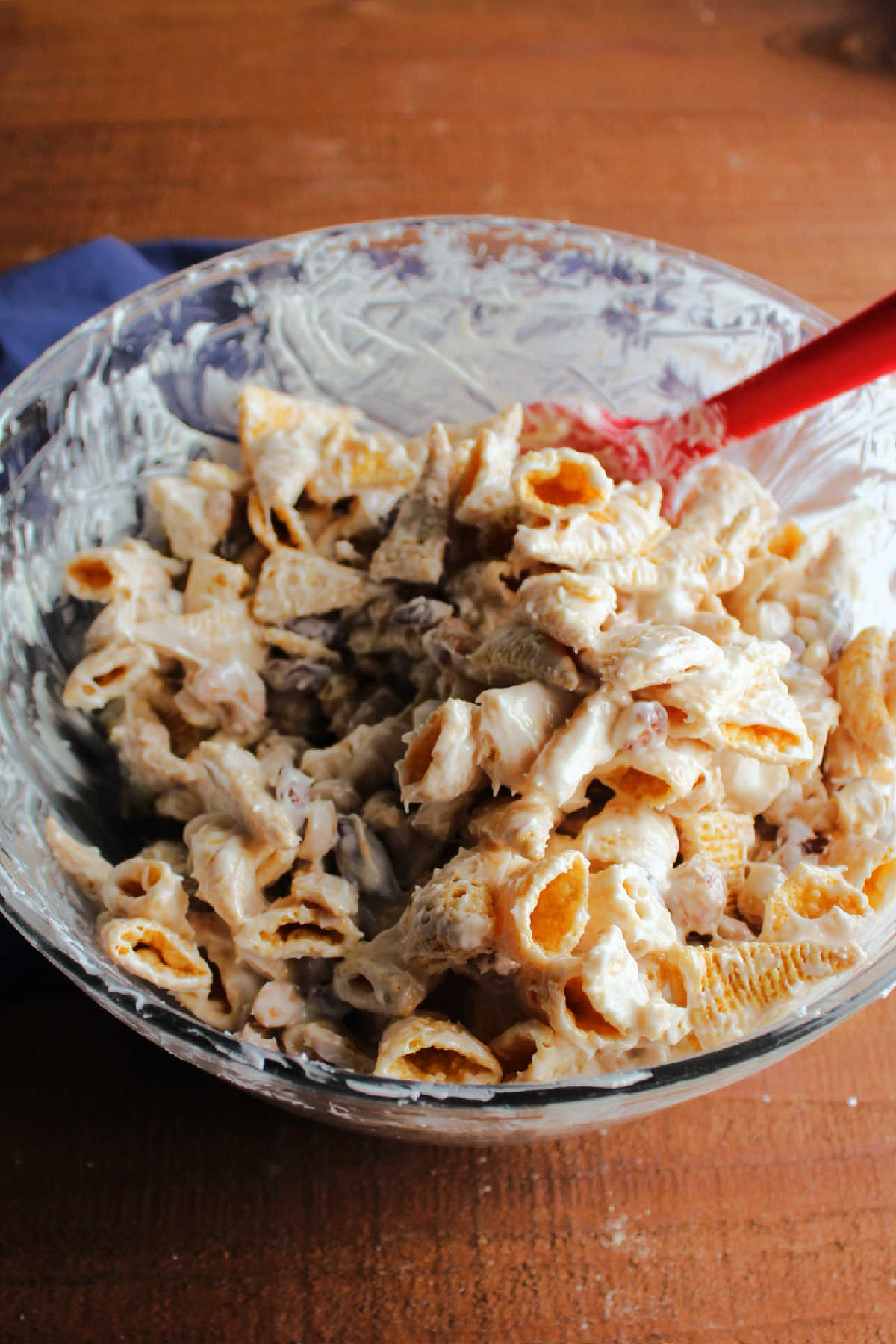 Mixing bowl filled with melted white chocolate, mixed nuts and bugles. 