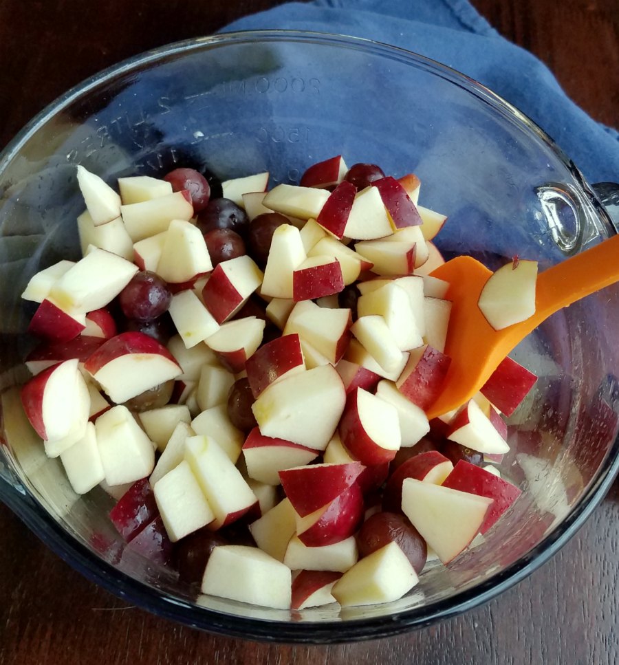bowl of chopped apples and whole purple grapes.
