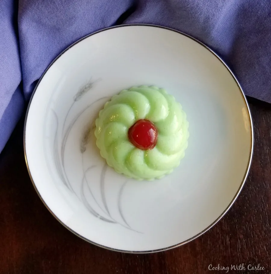 small molded jello salad on plate with red cherry on top