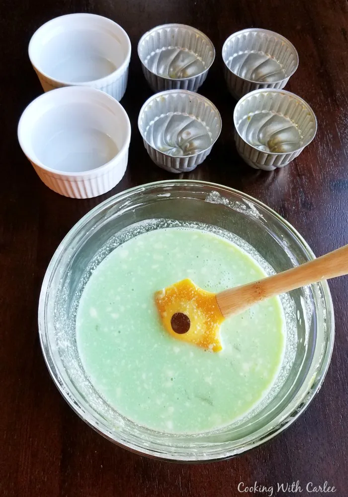 bowl of creamy green jello mixture with assortment of greased molds