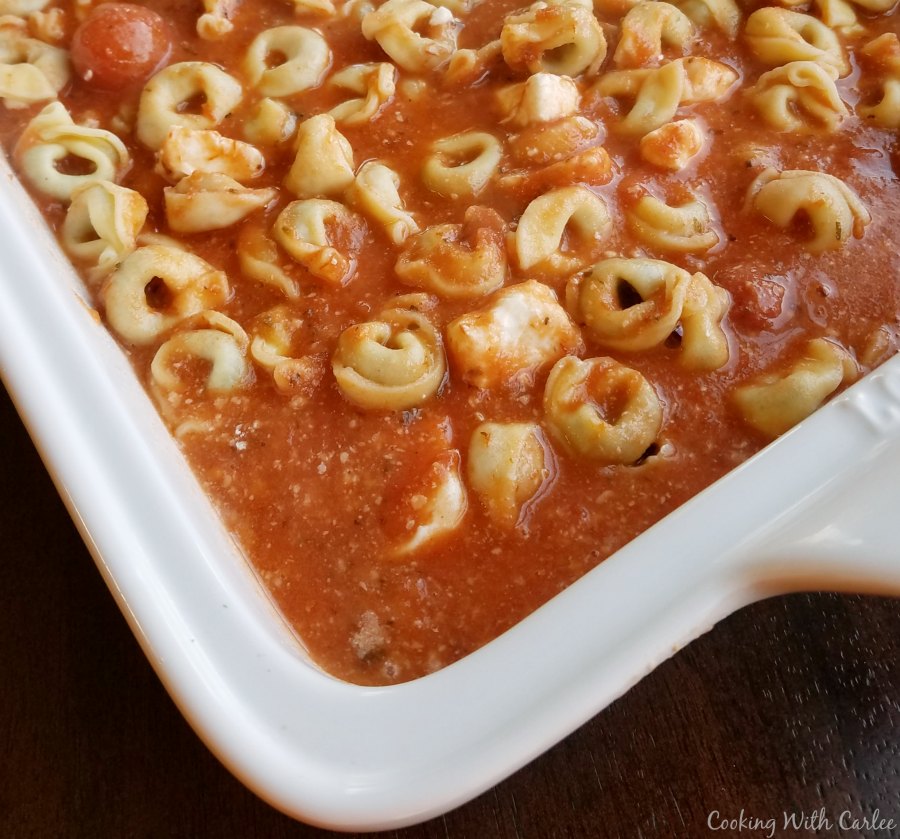 corner of baking dish filled with sauce and tortellini.
