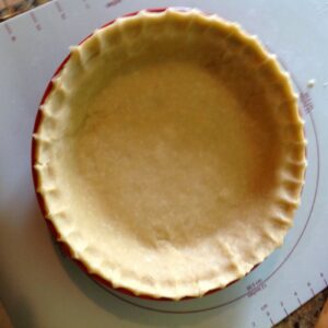 Flaky pie crust pastry in pie pan with fluted edges, ready for filling.