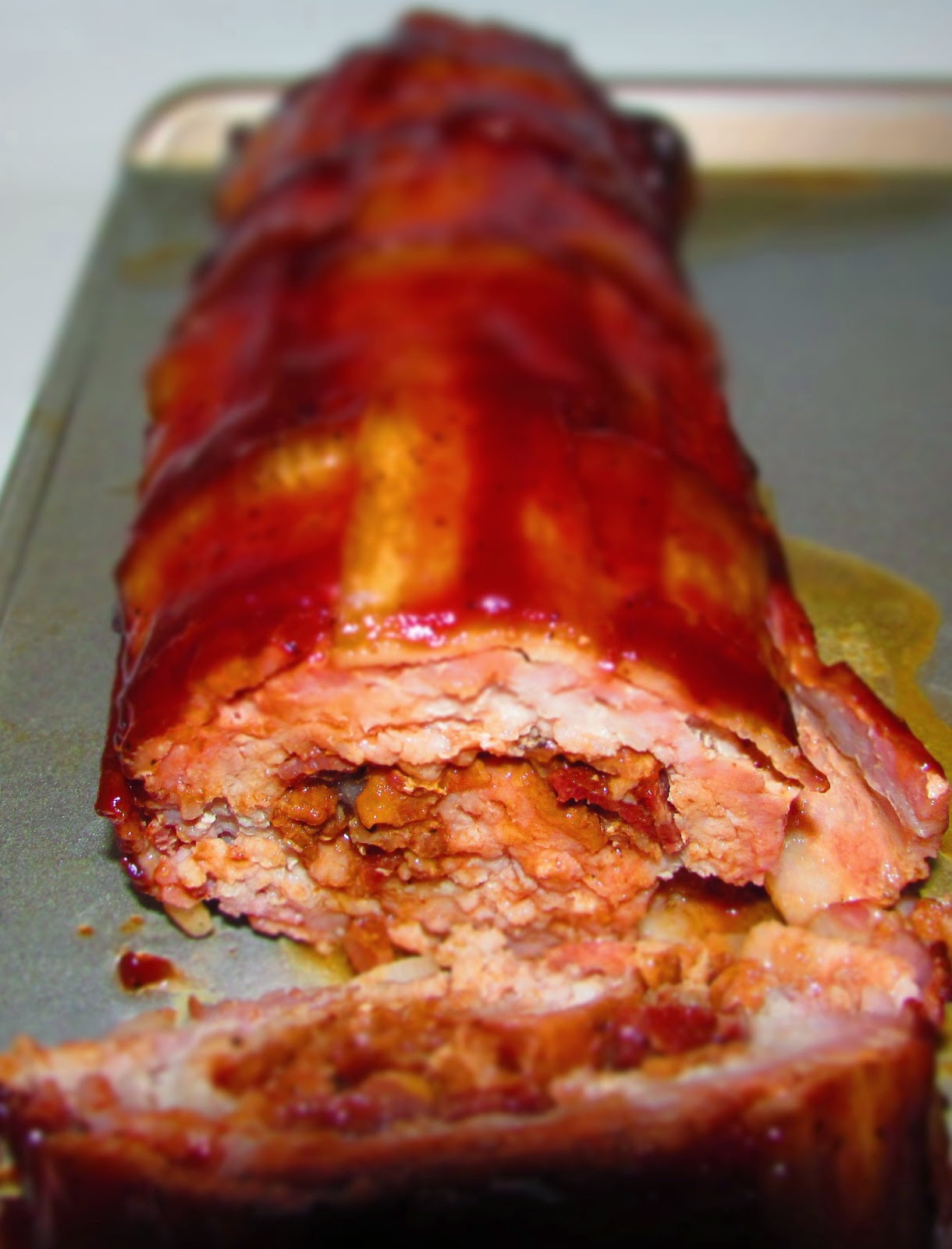bbq bacon explosion being cut into slices showing crumbled bacon center and bacon lattice weave exterior.