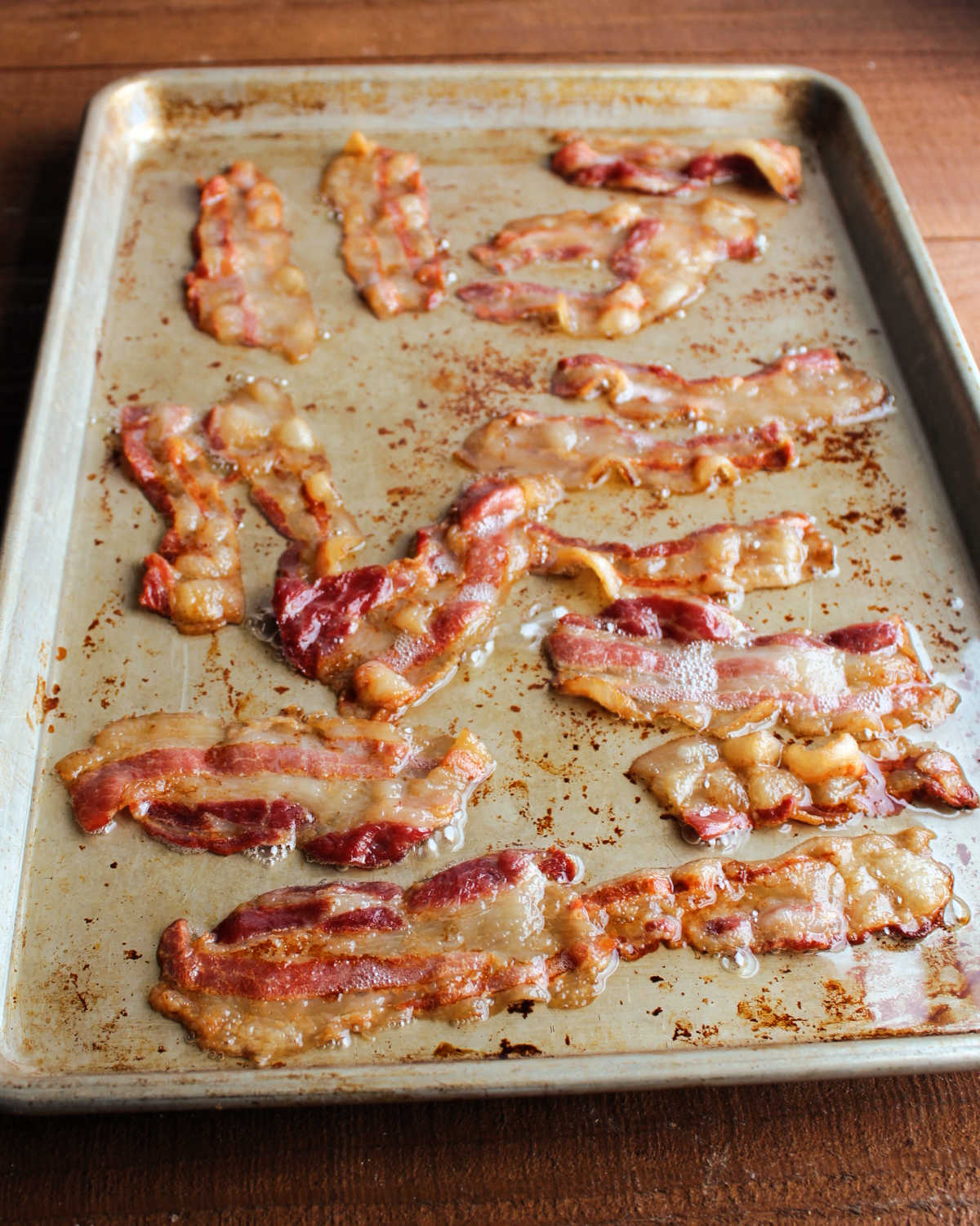 Sheet pan filled with freshly baked bacon slices and the accompanying bacon grease, ready to be drained and used in the middle of the bacon explosion.
