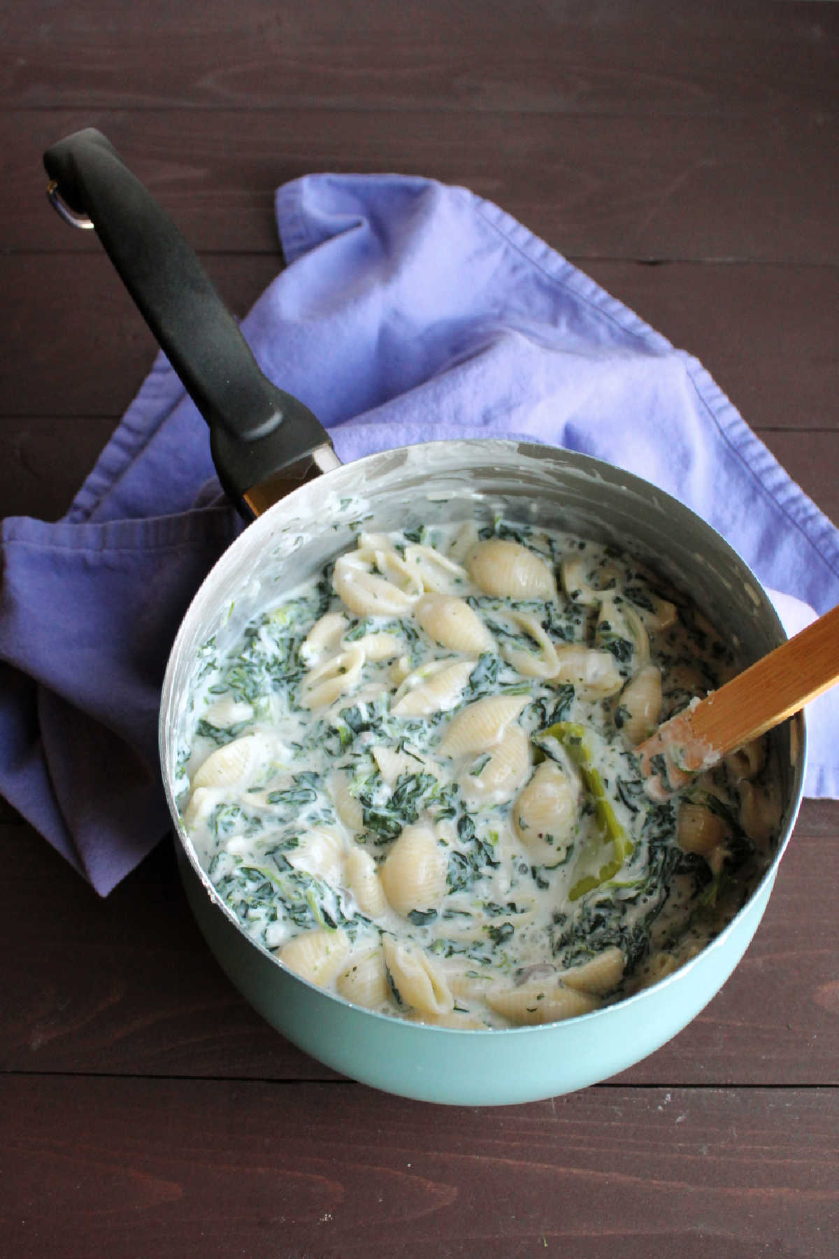 Saucepan of creamy spinach mac and cheese with mozzarella and Parmesan cheese. 