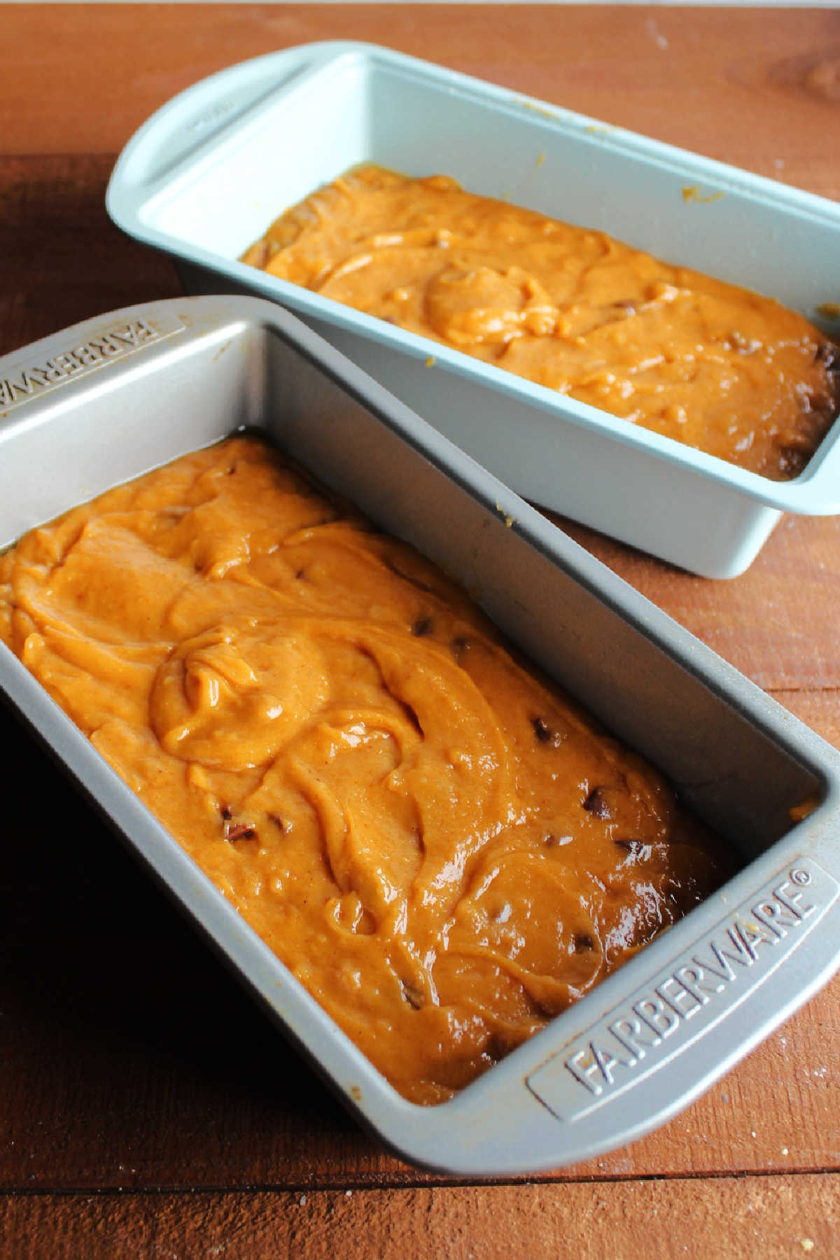Two loaf pans with pumpkin chocolate chip bread batter inside ready to go in the oven.