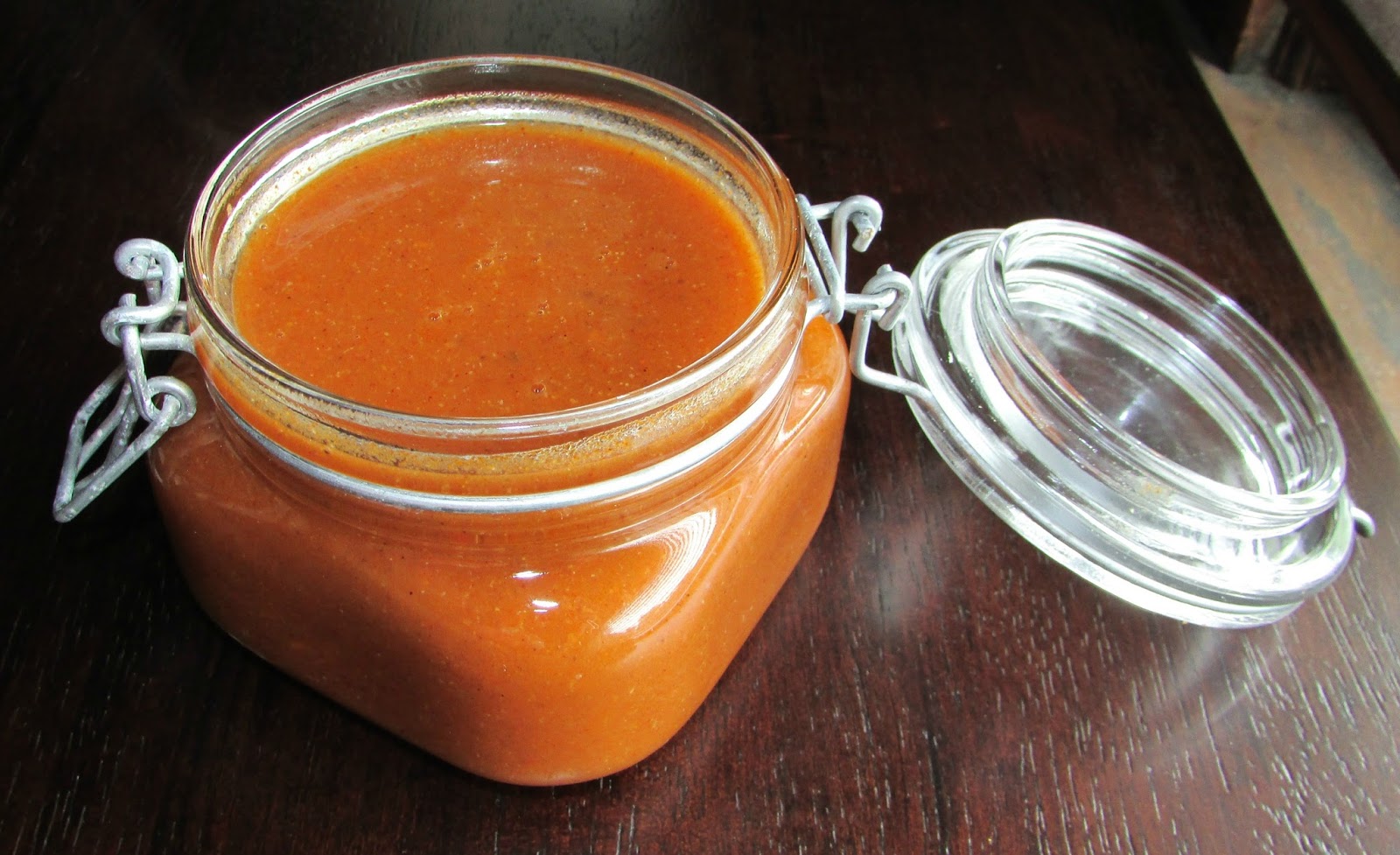 Open jar of homemade enchilada sauce showing red tomato based goodness inside.