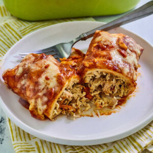Chicken enchilada with homemade red enchilada sauce and melted cheese on top.