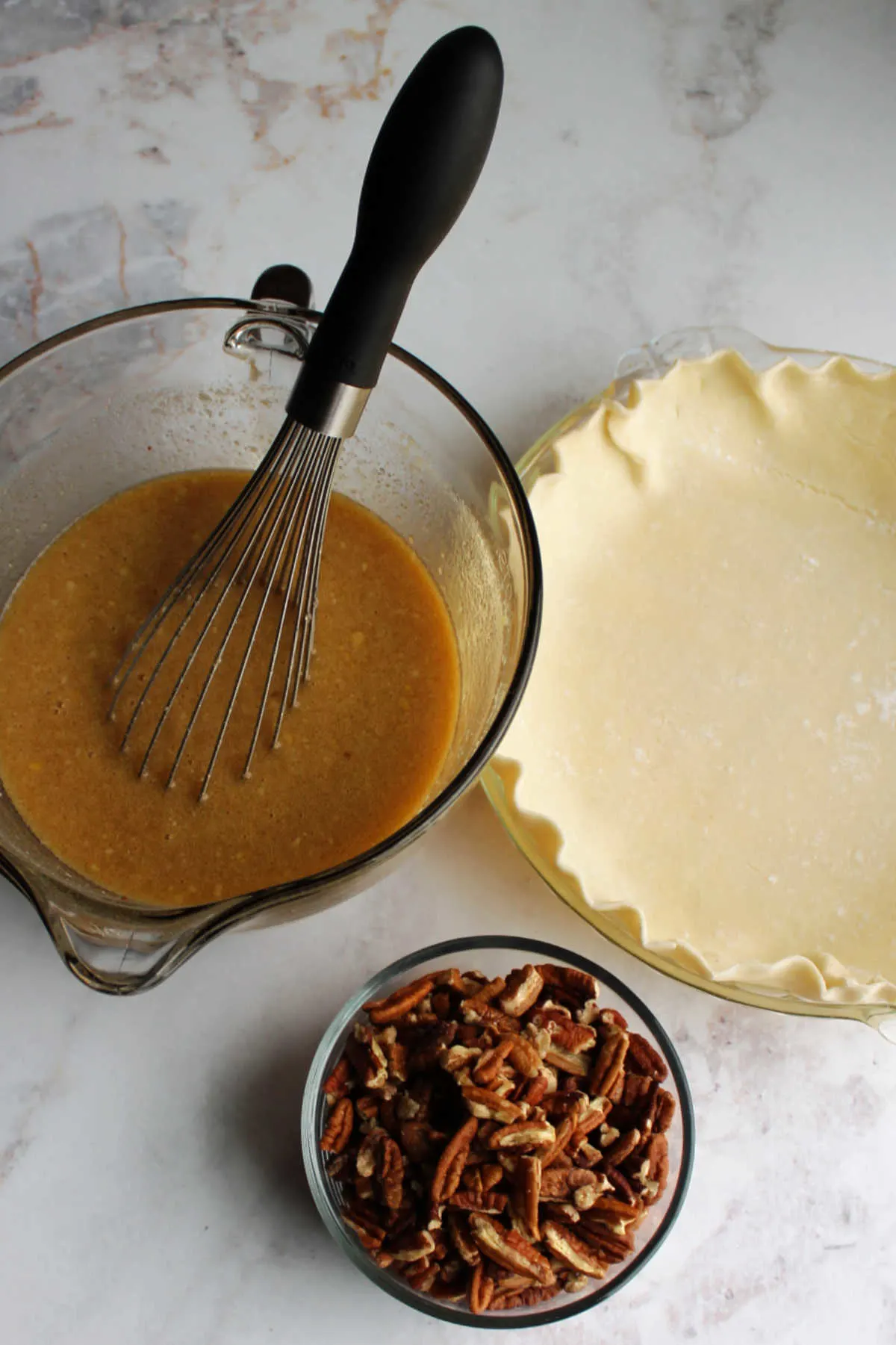 Pie crust in pan, bowl of honey maple mixture and bowl of pecans.
