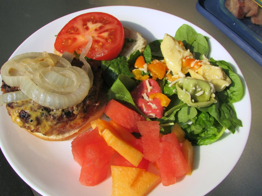 Dinner plate with stuffed lava burger, fresh fruit and a green salad.