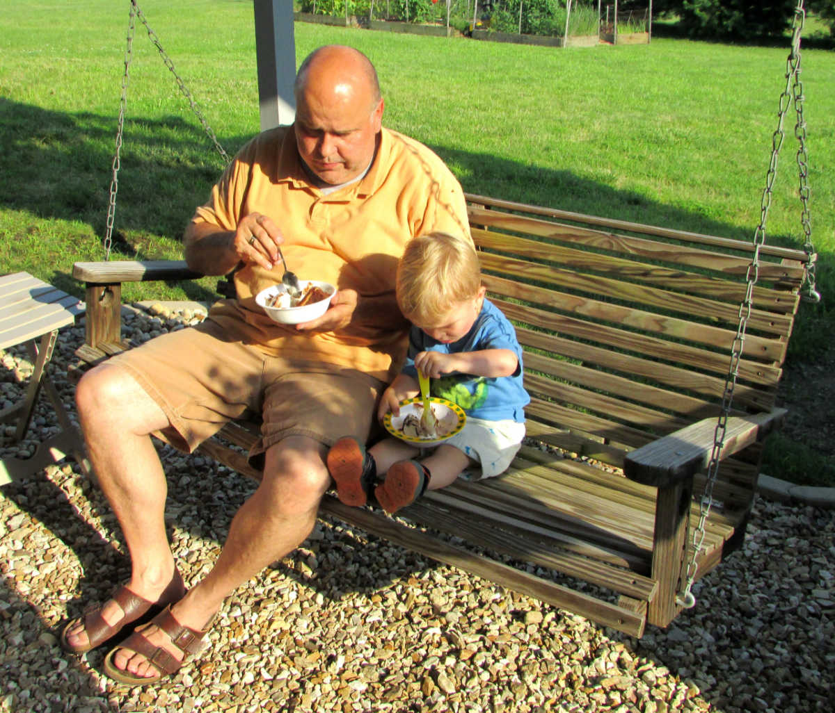 grandpa and grandson eating cake and ice cream on a porch swing.
