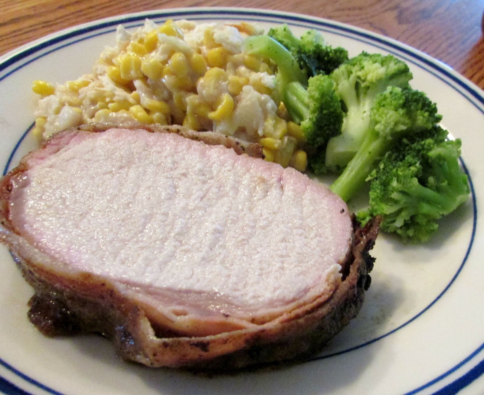 dinner plate with bacon wrapped pork loin, broccoli and scalloped corn