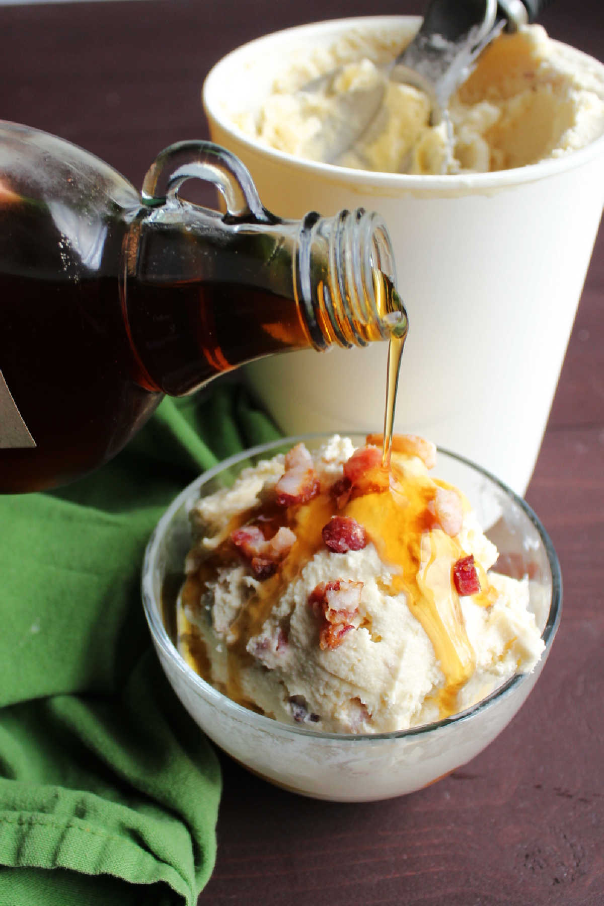 Pouring maple syrup over scoop of maple bacon ice cream. 
