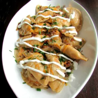 Homemade cheesy potato pierogi fried with bacon and topped with sour cream and chives.