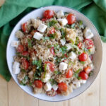 bowl of quinoa salad with tomatoes basil and mozzarella pearls