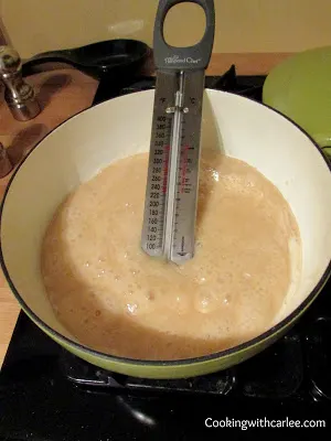 Caramel boiling in saucepan with candy thermometer.