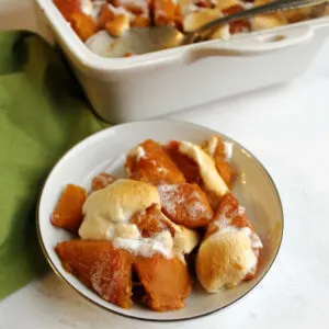 small dish of candied sweet potatoes with marshmallows in front of remaining pan.