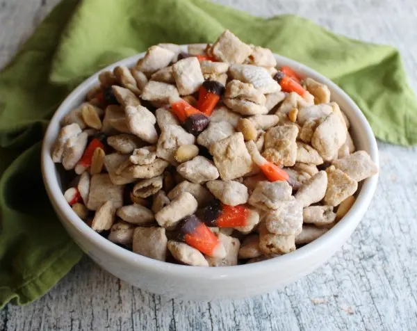 close bowl of white chocolate puppy chow mixed with candy corn and peanuts to make squirrel chow snack mix.