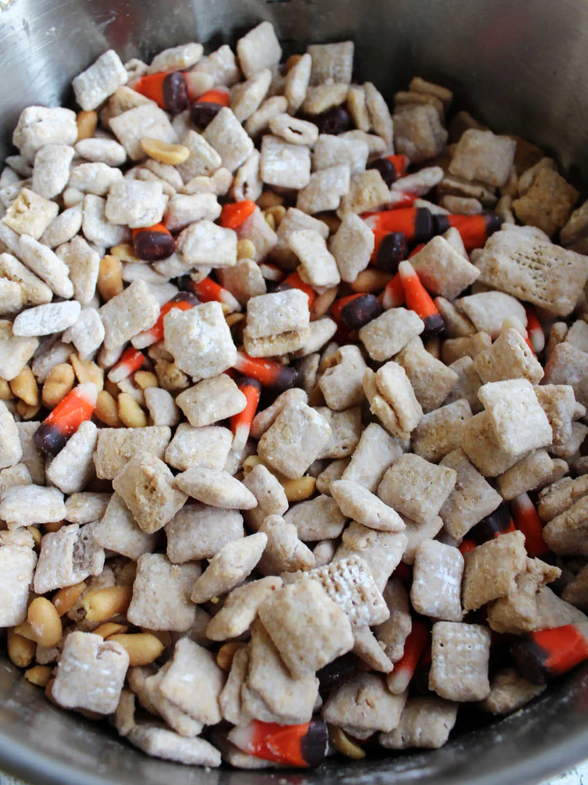 Close up of fall puppy chow with coated cereal mixed with candy corn and roasted peanuts. 