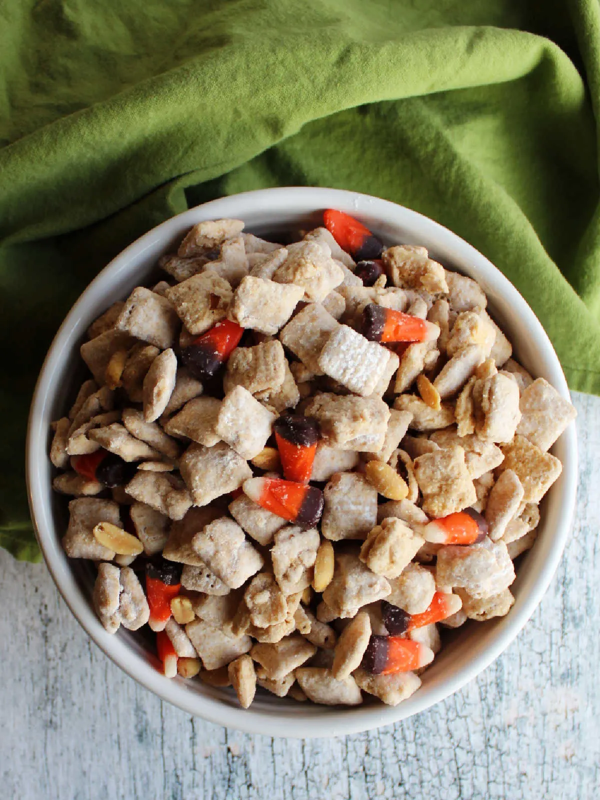 Bowl of fall puppy chow mix with peanuts and candy corn. 