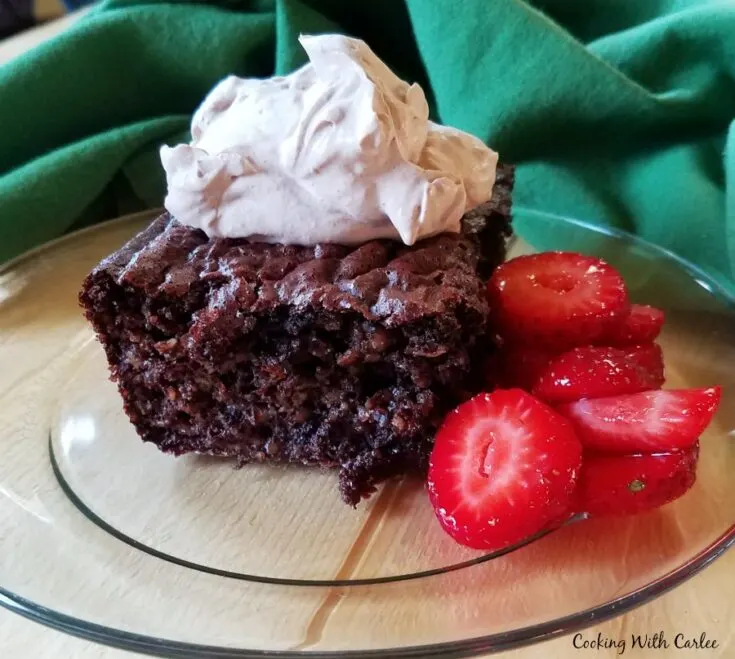 Piece of brownie baked oatmeal topped with cocoa whipped cream and served with sliced strawberries.
