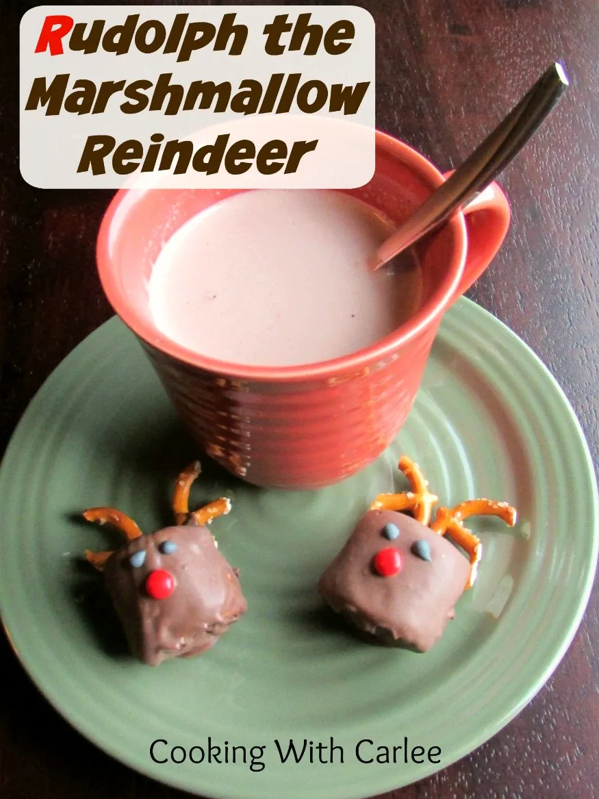 Mug of hot chocolate on plate with two chocolate dipped marshmallows decorated to look like Rudolph the red nosed reindeer.