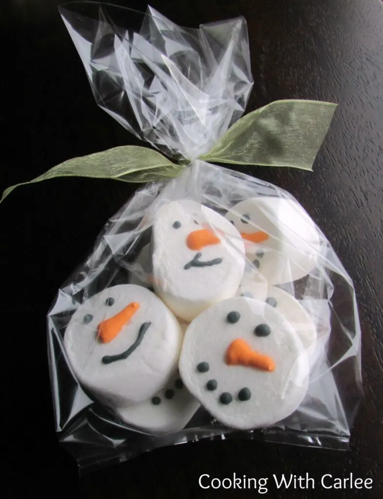 Cellophane bag filled with snowman decorated marshmallows with bow on top.