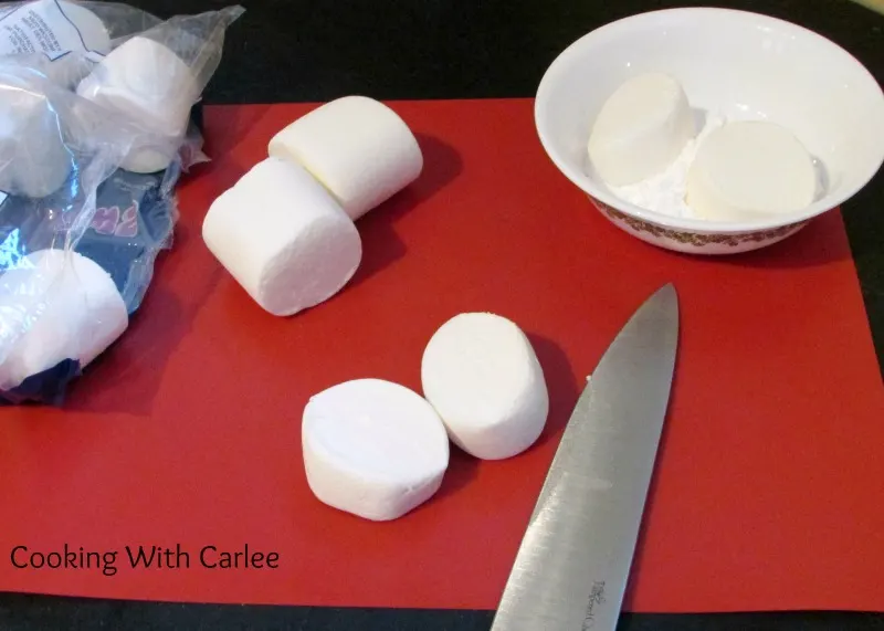 Cutting large marshmallows in half to be decorated.