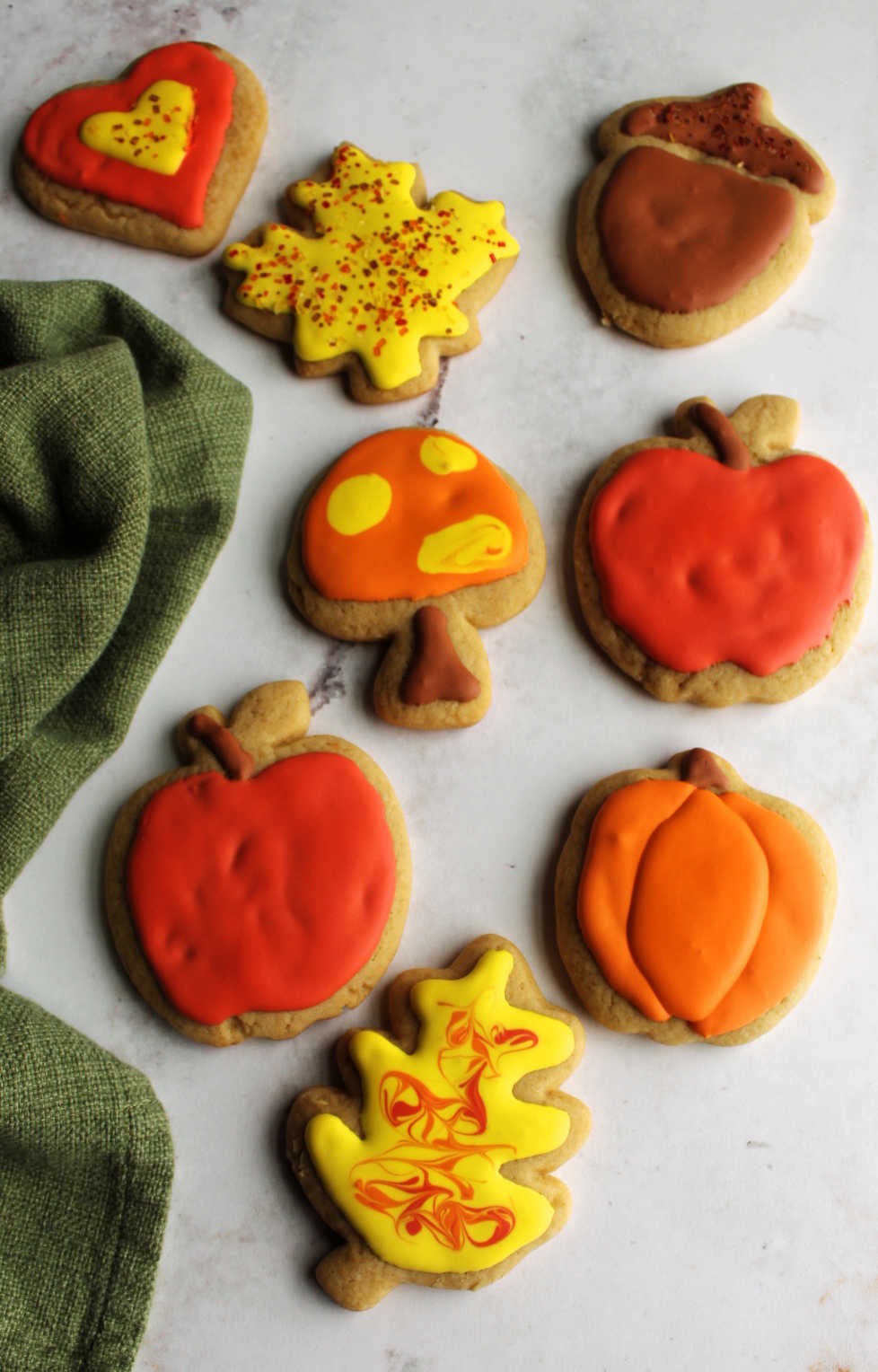 Iced cinnamon brown sugar cookies in shapes of pumpkins, apples, leaves, a mushroom and a heart.