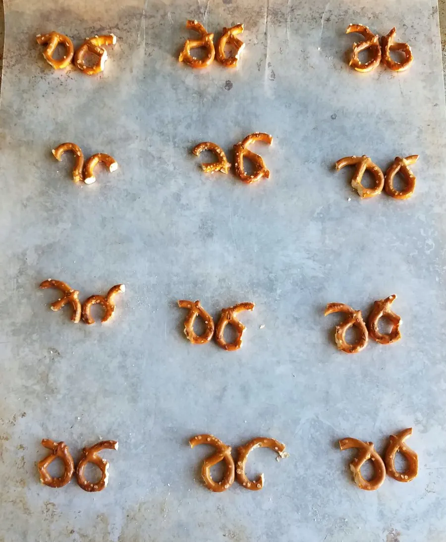 Pieces of mini pretzels arranged to look like antlers on baking tray waiting for chocolate and marshmallows.