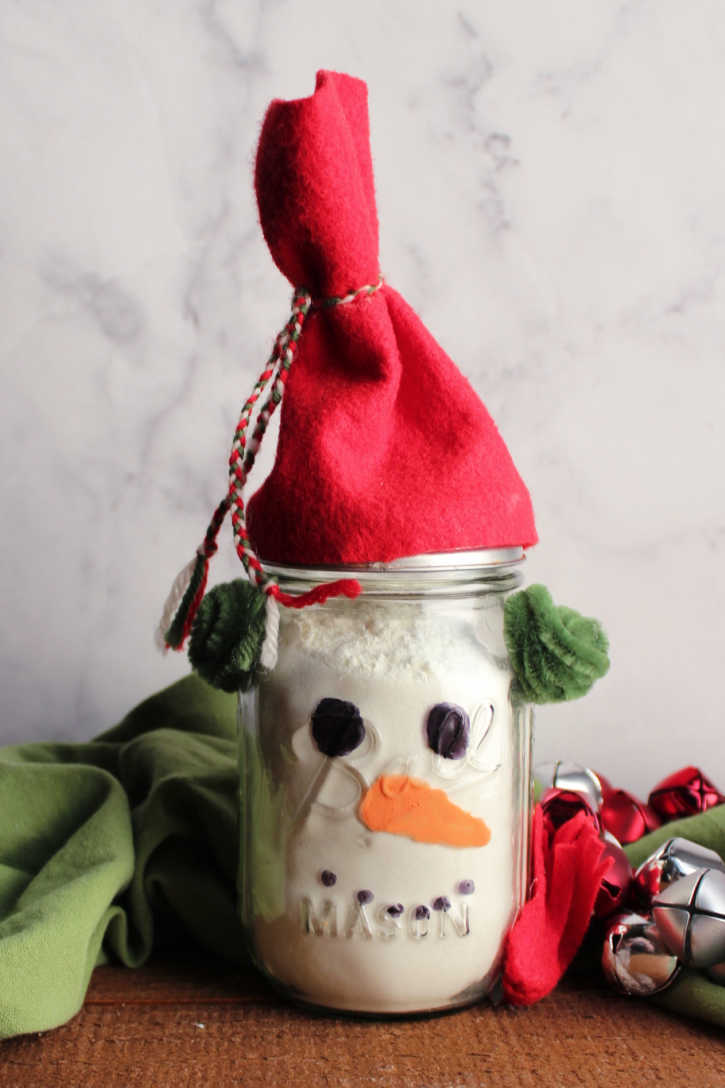 Finished snowman jar filled with white hot chocolate mix powder.