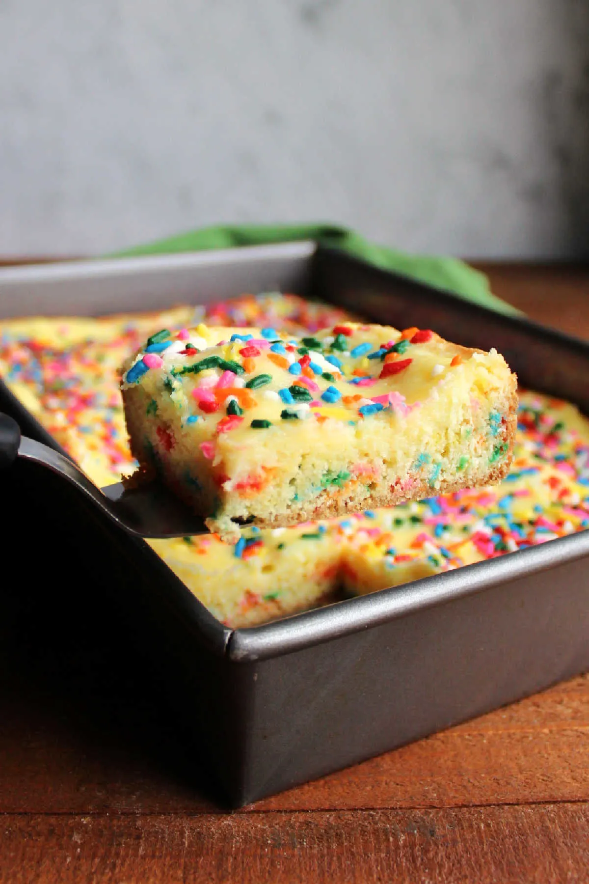 Lifting piece of baked confetti gooey butter cake out of the pan.
