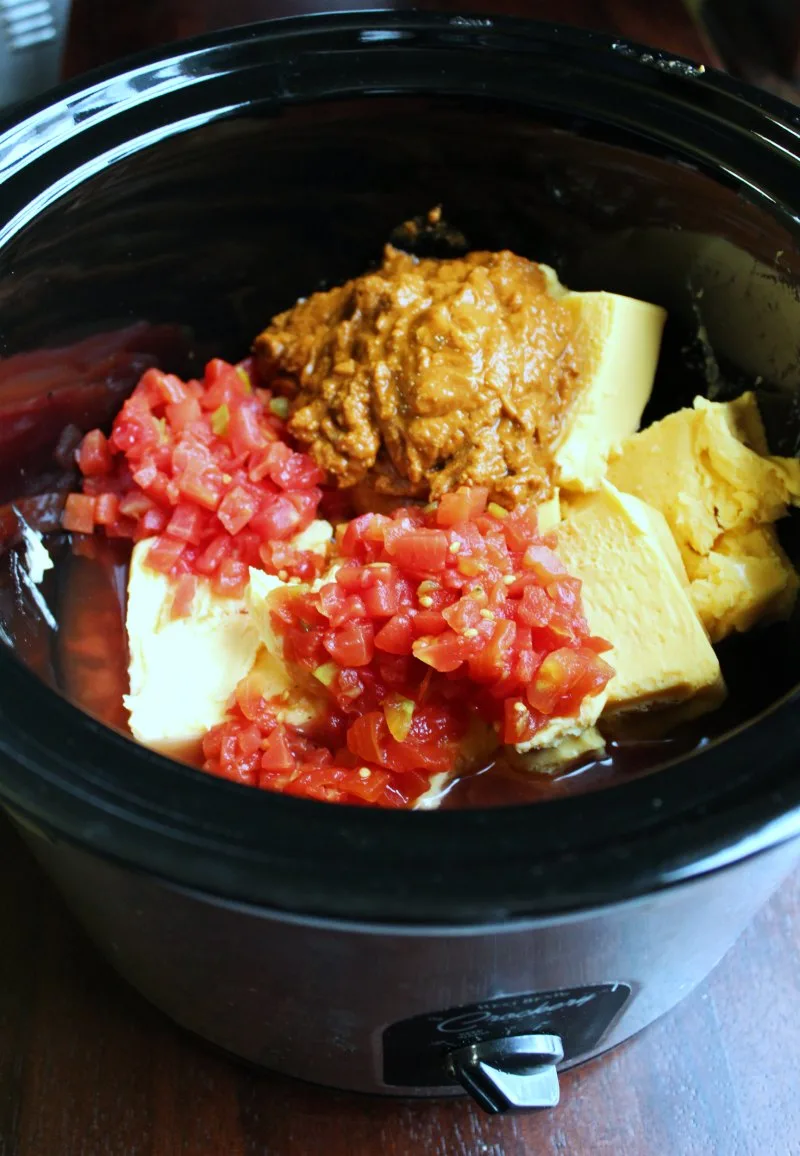 slow cooker filled with velveeta, rotel and queso ingredients.