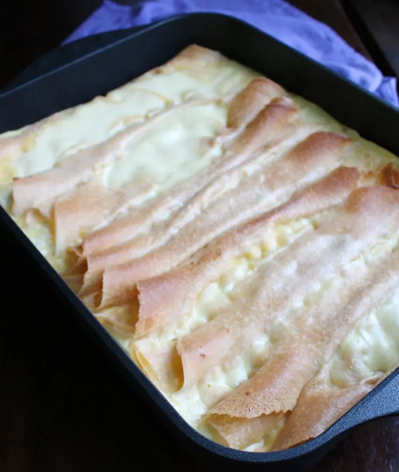 roasting pan filled with freshly baked cottage cheese stuffed crepes topped with creamy custard.