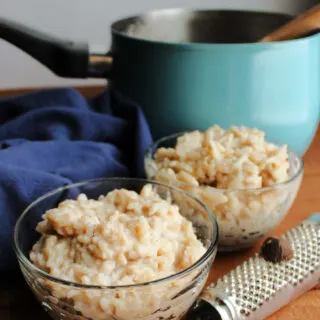 small bowls of banana honey rice pudding with nutmeg grater in front of teal saucepan.