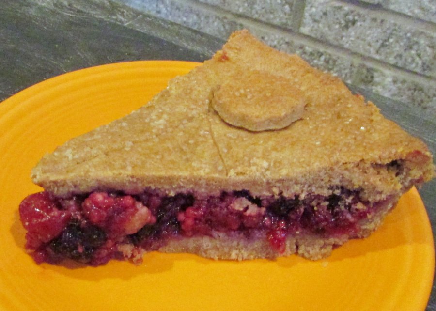 Slice of cherry berry pie with sugar dusted light brown crust on top and bottom.