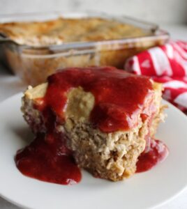 close up piece of strawberry cheesecake baked oatmeal drizzled with strawberry syrup.