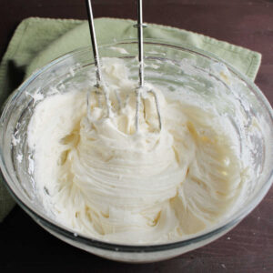 Glass mixing bowl filled with creamy cream cheese frosting ready to use.