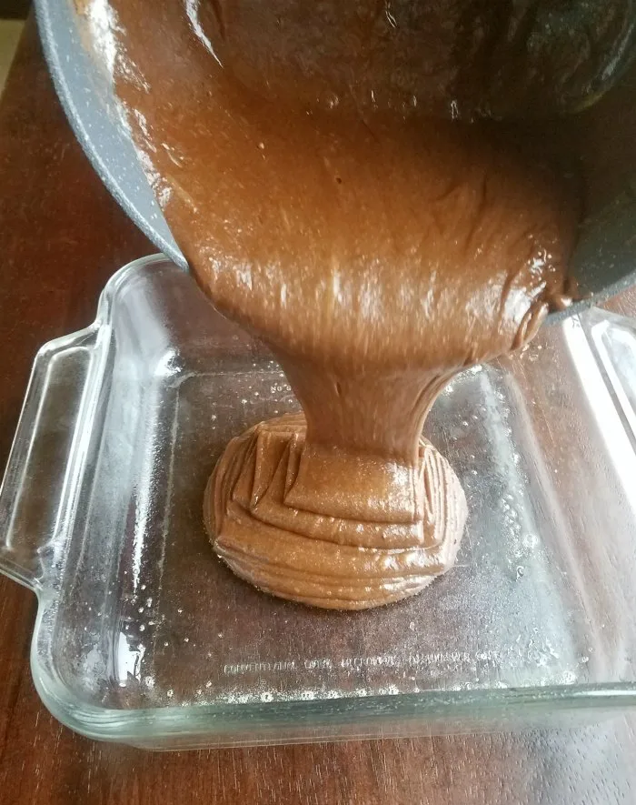 pouring brownie batter into greased pan to be baked. 
