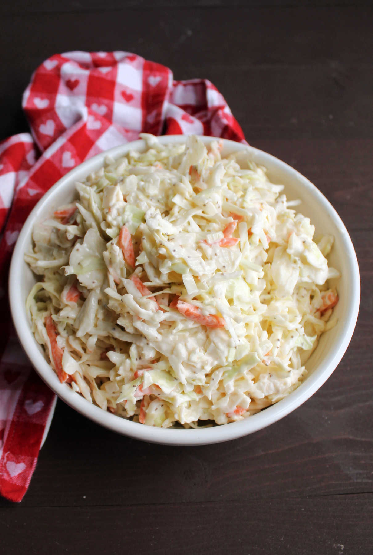 Looking down on a bowl of shredded cabbage with homemade coleslaw dressing, ready to eat. 