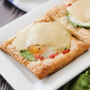 Puff pastry eggs benedict tart with spinach, ham and hollandaise sauce ready to eat.