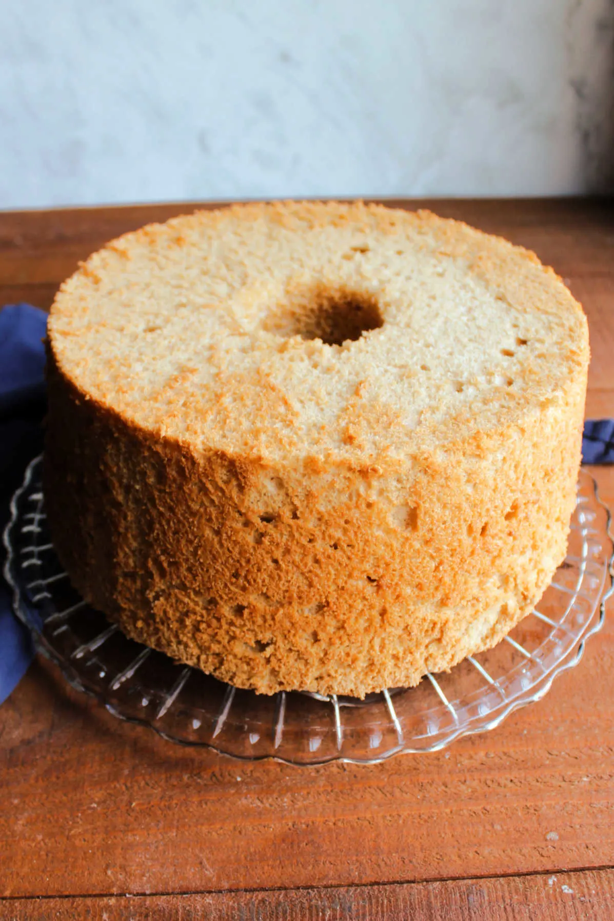 Cooled coffee angel food cake out of the pan and on a glass cake plate.