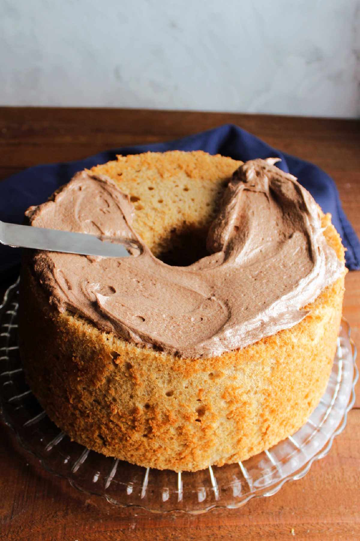 Spreading mocha mousse frosting over coffee angel food cake.