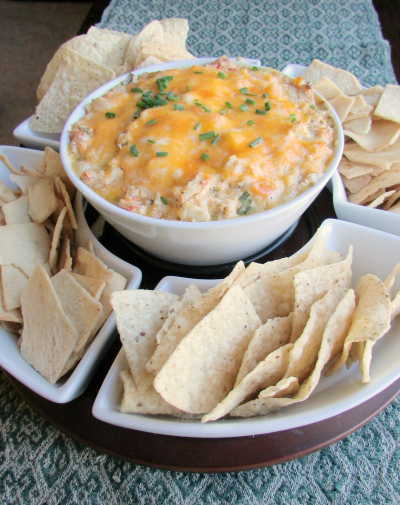 Chip and dip server with tortilla and pita chips with big bowl of hot gooey cheesy shrimp dip in center.